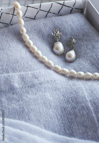 Pearl necklaces and earrings lay on green stones.