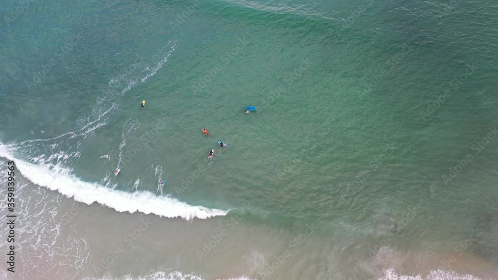 imagem aérea de bela praia com pessoas praticando surf, bodyboard, stand up e se banhando 