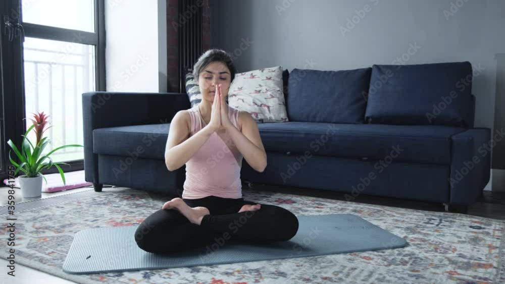 A attractive female practicing yoga in sportswear on a blue yoga mat at home. A attractive female practicing yoga in sportswear on a blue yoga mat at home.