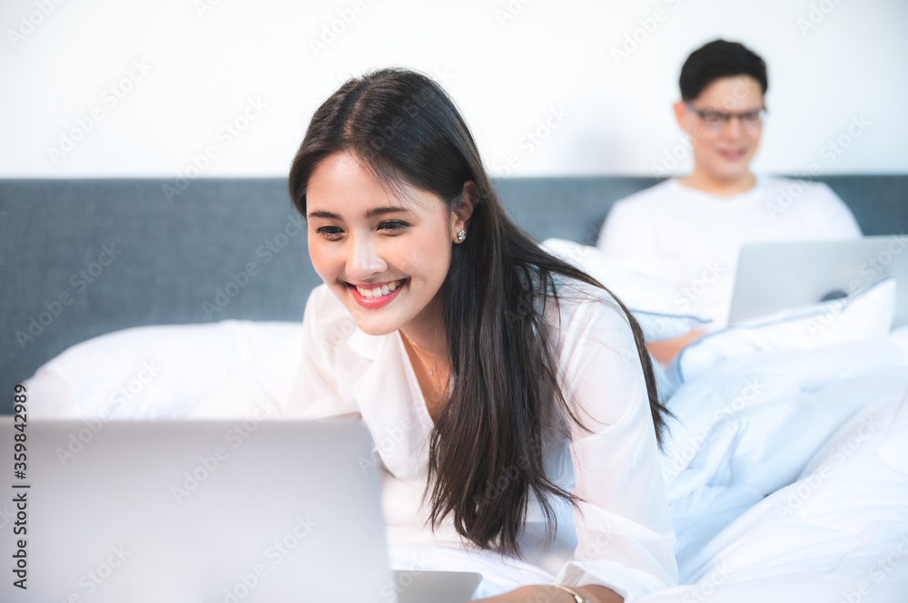 Young Asian business couple working on the bed, concept of working from home Young Asian business couple working on the bed, concept of working from home
