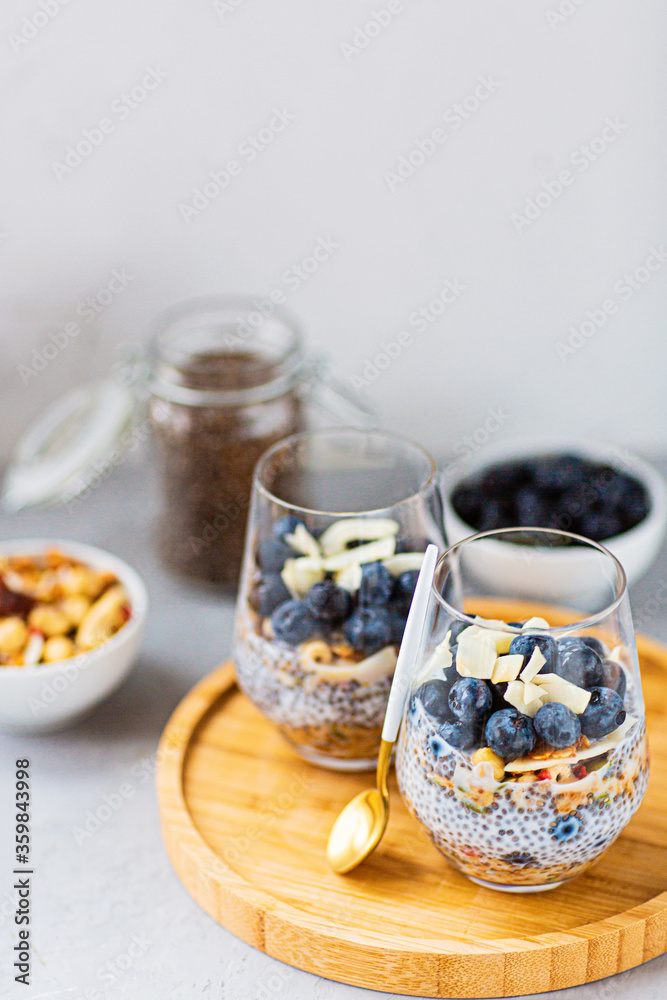 Chia pudding with granola and fresh blueberries in the glasses on a gray concrete background. Concept of healthy eating, healthy lifestyle, dieting, fitness menu. Selective focus. High quality photo Chia pudding with granola and fresh blueberries in the glasses on a gray concrete background. Concept of healthy eating, healthy lifestyle, dieting, fitness menu. Selective focus. High quality photo