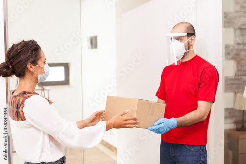 Delivery man wearing protection giving female costumer her order. © DC Studio