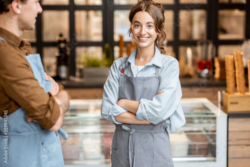 Fotografía Portrait of a two cheerful employees of a cafe or small shop standing in front o