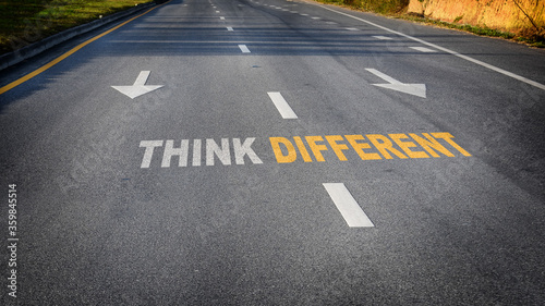 Think different word with white arrow and dividing lines on black asphalt road surface, business challenge concept and success idea