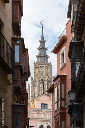 One of the towers of the cathedral of Toledo is visible among the modern facades of its streets