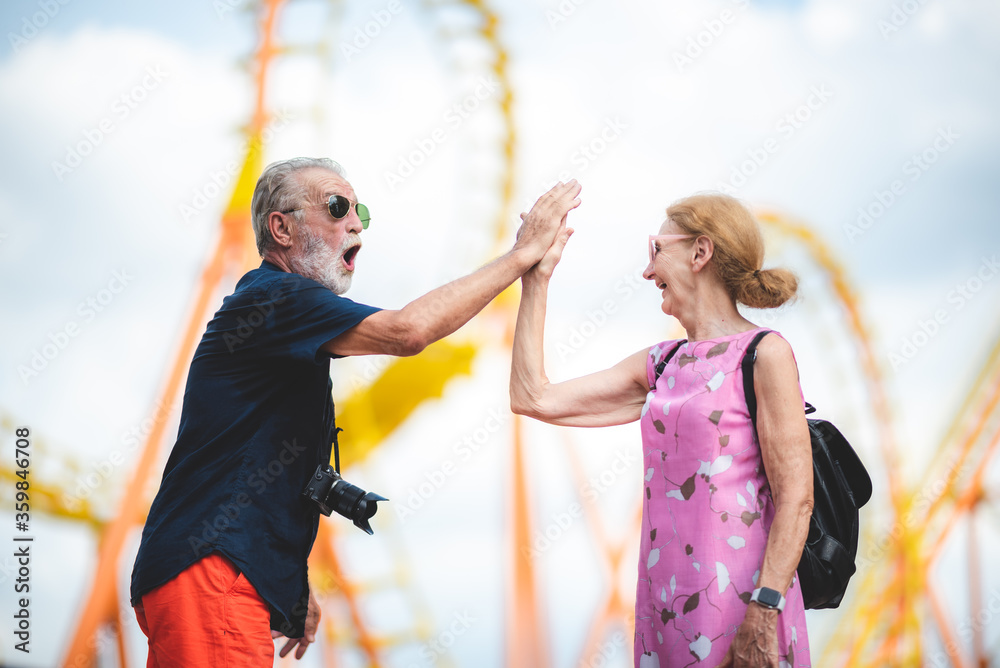 Obraz premium Senior couple enjoying and happy to travel and playing at an amusement theme park, concept of love and happy with old 60's senior people