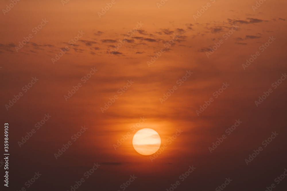 View of the sun behind the clouds during sunrise