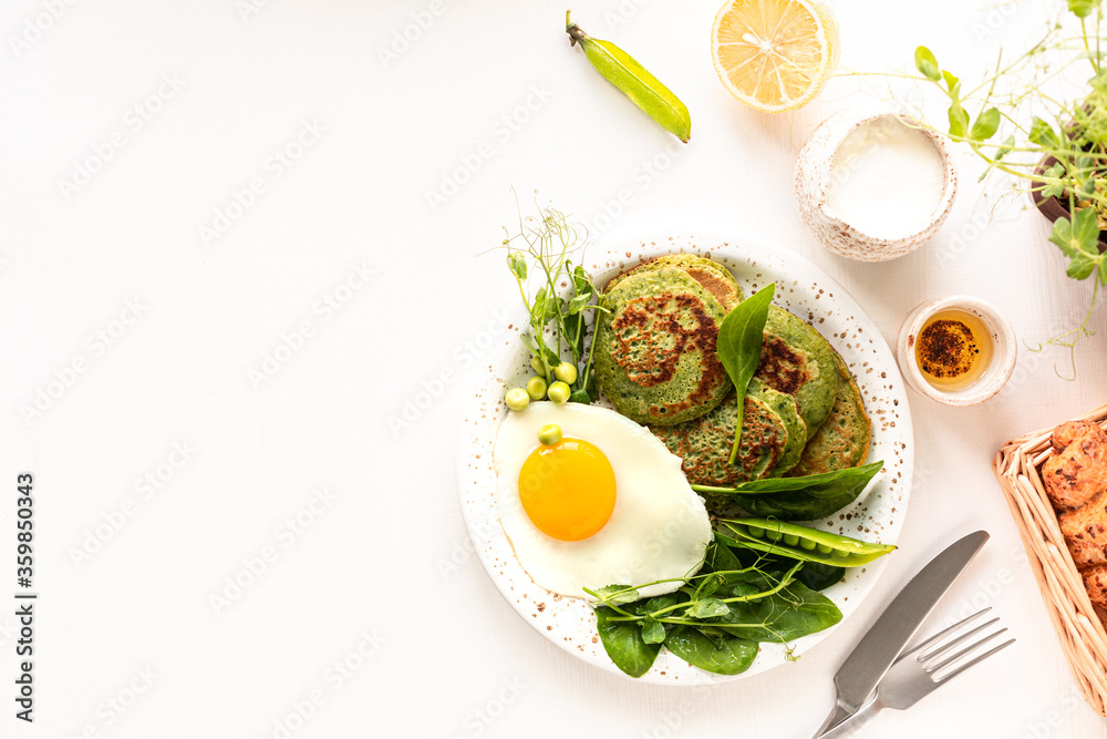 Tasty healthy breakfast. Green pancakes with spinach, egg and young green peas. top view. copy space. Tasty healthy breakfast. Green pancakes with spinach, egg and young green peas. top view. copy space.