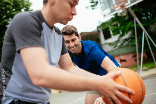 Two young men playing basketball in the park. Friends having a friendly match outdoors 