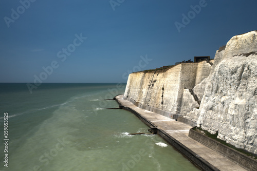 The white chalk cliffs in East Sussex Peacehaven an aerial view of the path below the spectacular cliffs with the English Channel calm at high tide.
