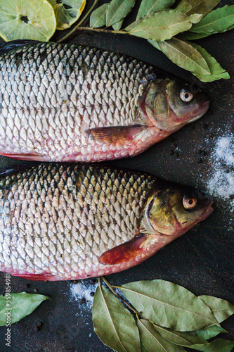 Two river crucians prepared for frying on a wooden table.