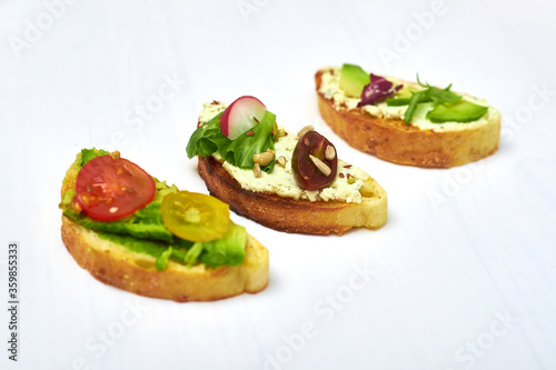 Ciabatta with cream cheese, avocado, various vegetables. Vegetarian sandwiches on a white background.