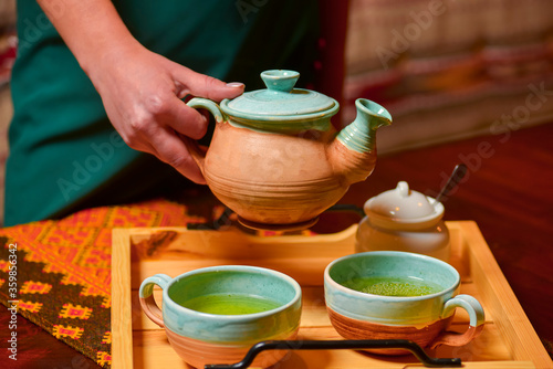 Composition with tea set. Traditional Ukrainian ceramic tea set. Tea-time. Woman pouring tea into a cup.