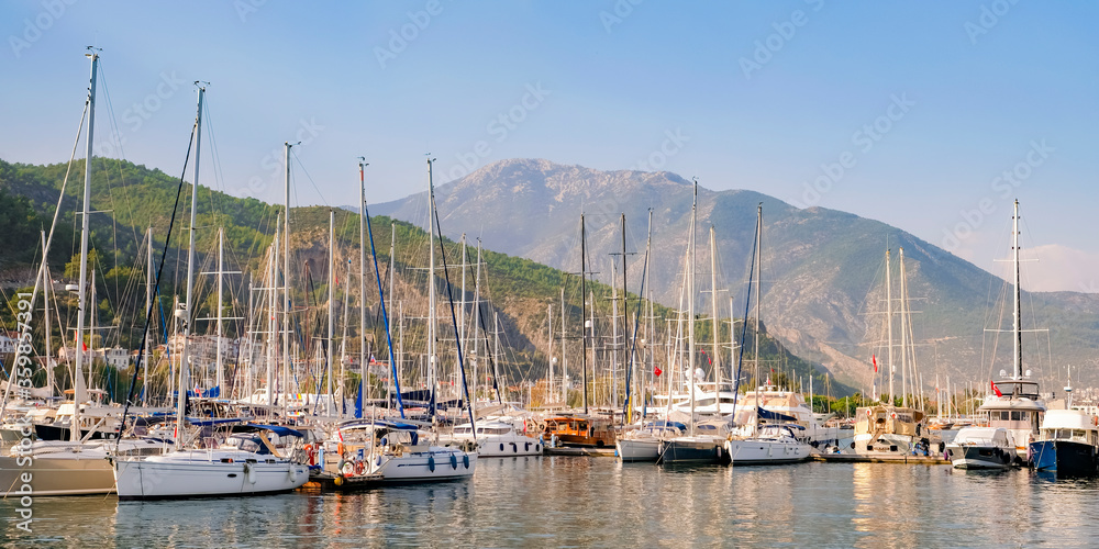 Luxury yachts docked in sea port at sunset. A stunning view of mega yachts in the port. Mountains background.