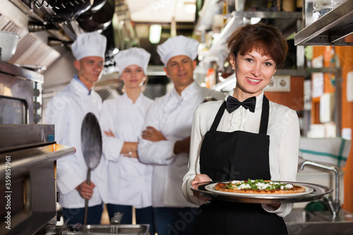 Waitress with ordered dish in kitchen