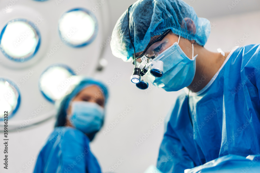 Professional anesthesiologist doctor medical team and assistant preparing patient to gynecological surgery performing operating with surgery equipment in modern hospital operation emergency room
