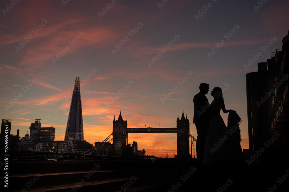 Silhouette of a wedding bride and groom at sunset with London skyline in the background showing Tower bridge and the Shard in the background