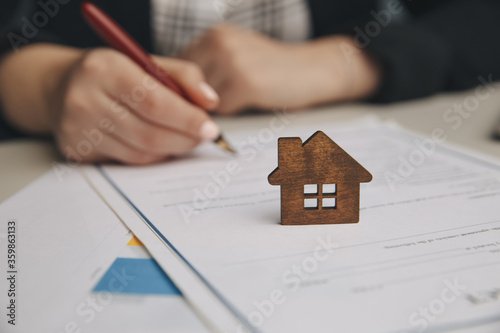 Valokuva Close up wooden toy house with Woman signs a purchase contract or mortgage for a home, Real estate concept
