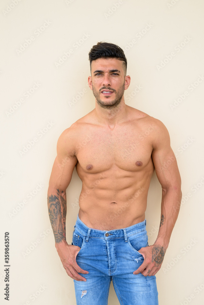 Happy young handsome muscular Persian man smiling shirtless