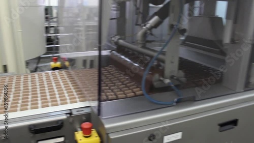 An automatic conveyor for the production of sweet glazed chocolates does its job in a confectionery factory. Panorama.