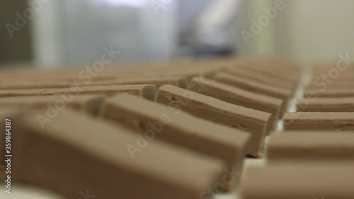 Sliced ​​pieces for making sweet chocolate glazed sweets move along a conveyor belt in a confectionery factory. Close-up video.
