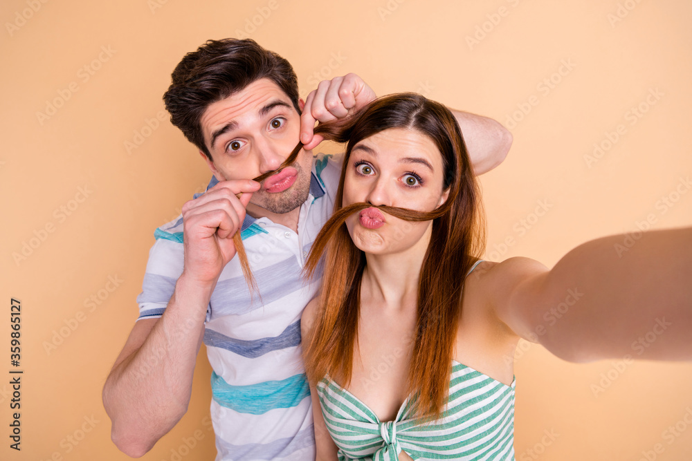 Portrait of funny hipster two people married man woman enjoy travel trip blogging make selfie fake mustache wear casual striped t-shirt dress skirt isolated over pastel color background