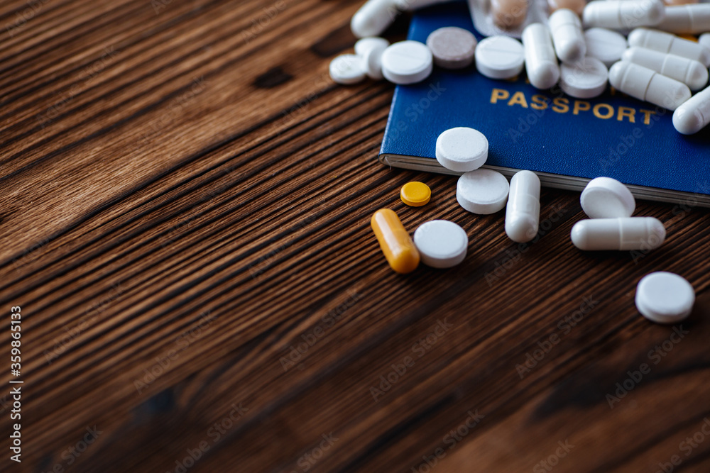 A pills, passport on a wooden background. COVID-19 and travel concept. Copy space