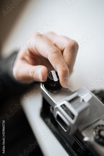 Male hand reloading film retro camera on a white table. Horizontal