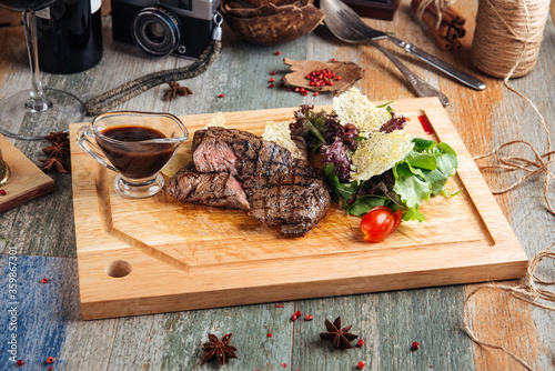 Horse meat steak with sauce on the wooden board photo