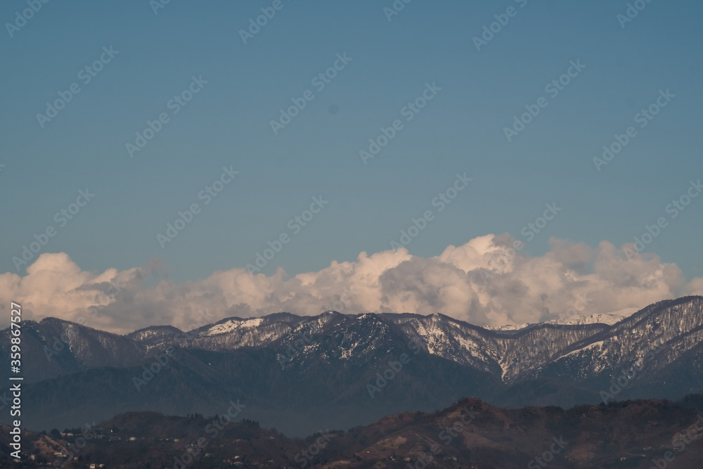 View of the foothills of the Caucasus. High peaks are covered with snow. Mountains against the blue sky. Day. Sunny. Georgia.