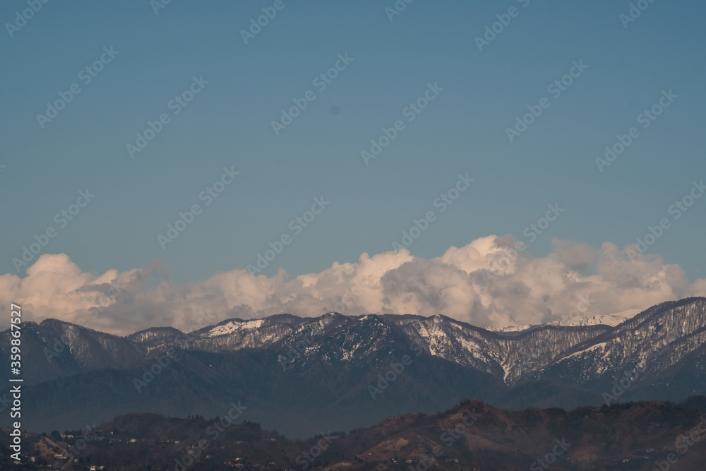 View of the foothills of the Caucasus. High peaks are covered with snow. Mountains against the blue sky. Day. Sunny. Georgia. View of the foothills of the Caucasus. High peaks are covered with snow. Mountains against the blue sky. Day. Sunny. Georgia.