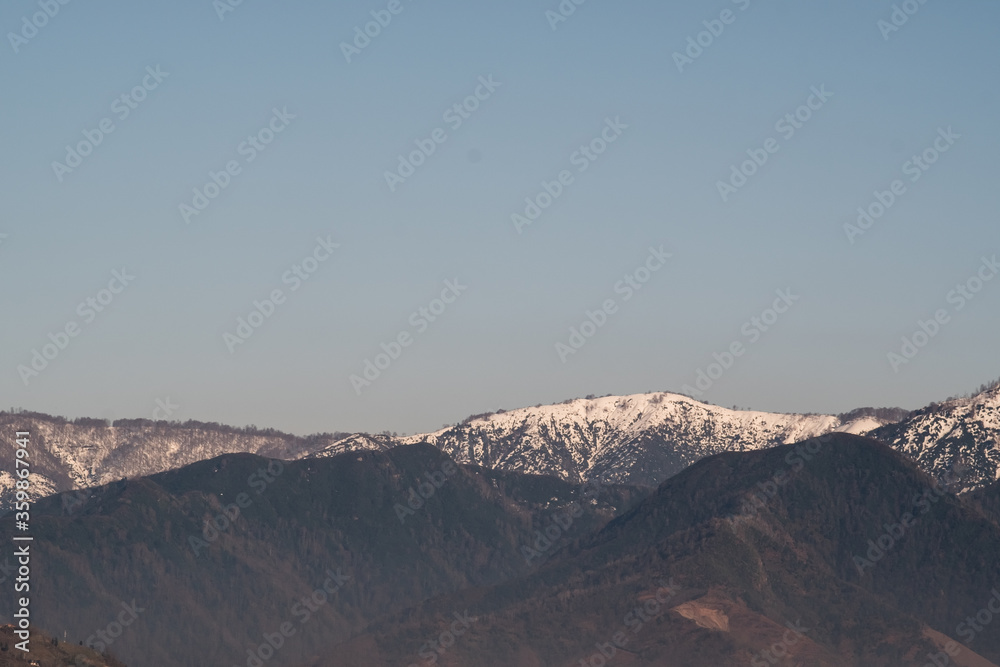 View of the foothills of the Caucasus. High peaks are covered with snow. Mountains against the blue sky. Day. Sunny. Georgia.