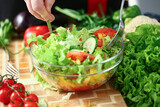 Close up of male hands cooking vegetable salad with tomatoes, cucumber and lettuce