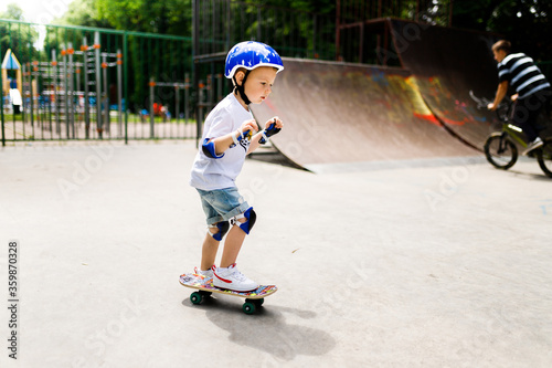 Boy with a skate in a skate park. The boy learns to skate, in full protection.