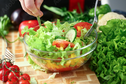 Close up of male hands cooking vegetable salad with tomatoes, cucumber and lettuce