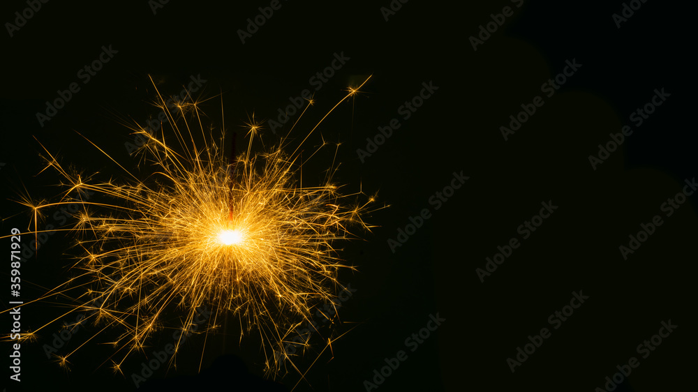 Happy New Year, sparkling burning sparkler or salute on a black background. Holiday concept, background, copy space
