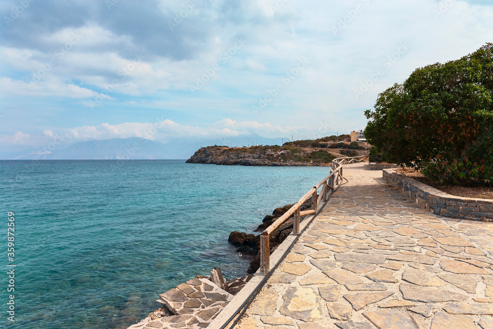 fragment of a stone path with wooden railings along the coast in the Greek resort town of Agios Nikolaos
