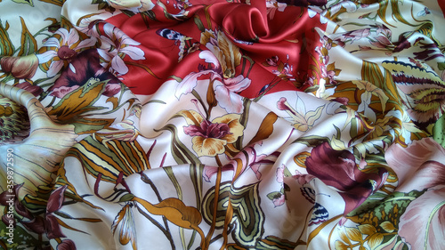 Silk fabric with an amazing colorful floral pattern is laid out in waves. Natural multi color smooth satin with a rich color scheme is perfect for the background .
