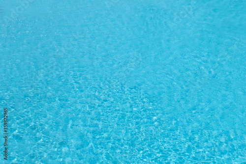 Blue pool water with solar reflections, transparent and clean, slightly heated by sunlight and not cold