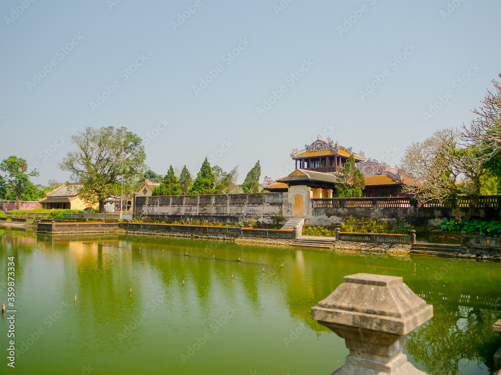 Hue, Vietnam - September 13 2017: Close up of old beautiful temple, with an artifical pond in front, reflected in the water, located in Hue city, Vietnam
