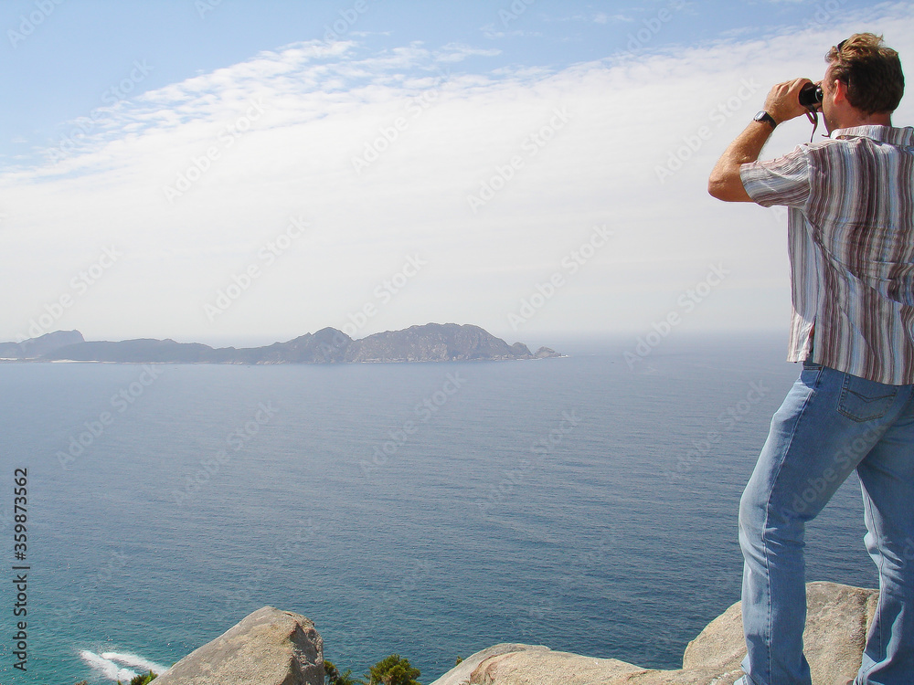 Hombre no reconocible observando con prismáticos la Ría de Vigo (España), al fondo las islas Cíes. Hombre no reconocible observando con prismáticos la Ría de Vigo (España), al fondo las islas Cíes.