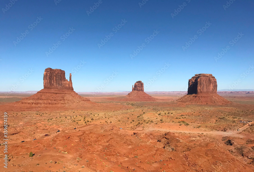 Amazing view of Monument Valley with red desert and blue sky and clouds in the morning. Monument Valley in Arizona with West Mitten Butte, East Mitten Butte, and Merrick Butte.	