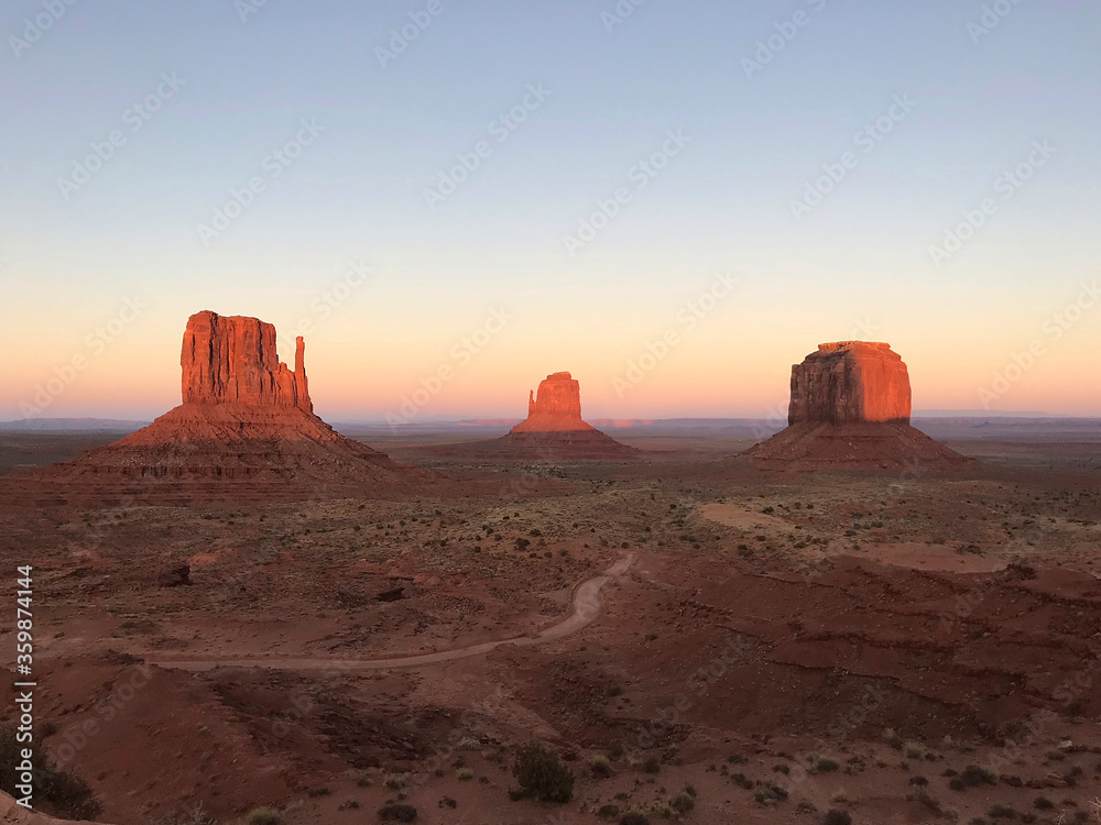 Amazing view of Monument Valley with red desert and blue sky and clouds in the morning. Monument Valley in Arizona with West Mitten Butte, East Mitten Butte, and Merrick Butte. Amazing view of Monument Valley with red desert and blue sky and clouds in the morning. Monument Valley in Arizona with West Mitten Butte, East Mitten Butte, and Merrick Butte.