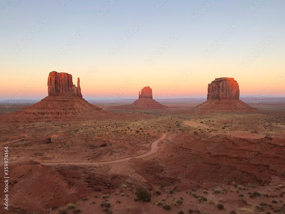 Amazing view of Monument Valley with red desert and blue sky and clouds in the morning. Monument Valley in Arizona with West Mitten Butte, East Mitten Butte, and Merrick Butte.	