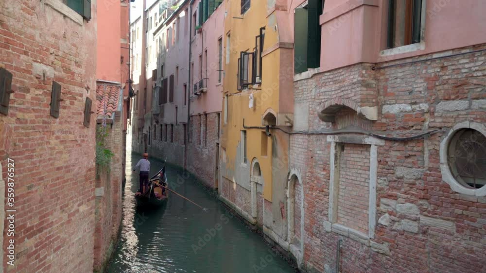 Gondolier rowing on a quiet narrow canal. Gondolier rowing on a quiet narrow canal.