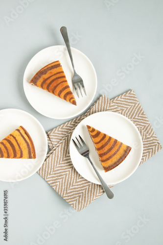 Marble cake (zebra) on light grey background. Pieces on white plates. T