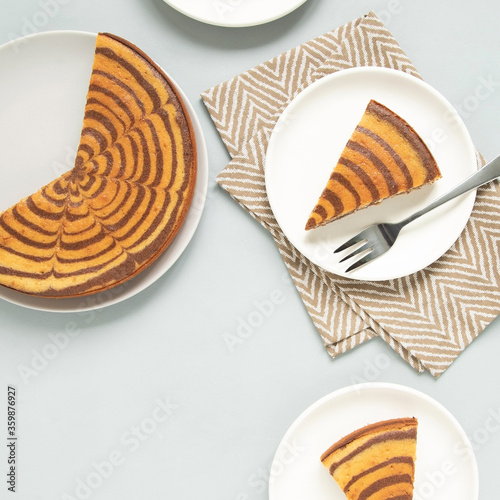 Marble cake (zebra) on light grey background. Pieces on white plates.