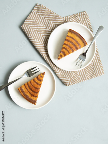 Marble cake (zebra) on light grey background. Pieces on white plates.