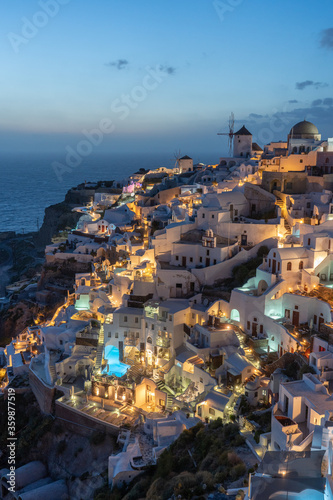 Oia in Santorini Greece taken at dusk looking towards the windmills and villas with swimming pools at night.  © Chris