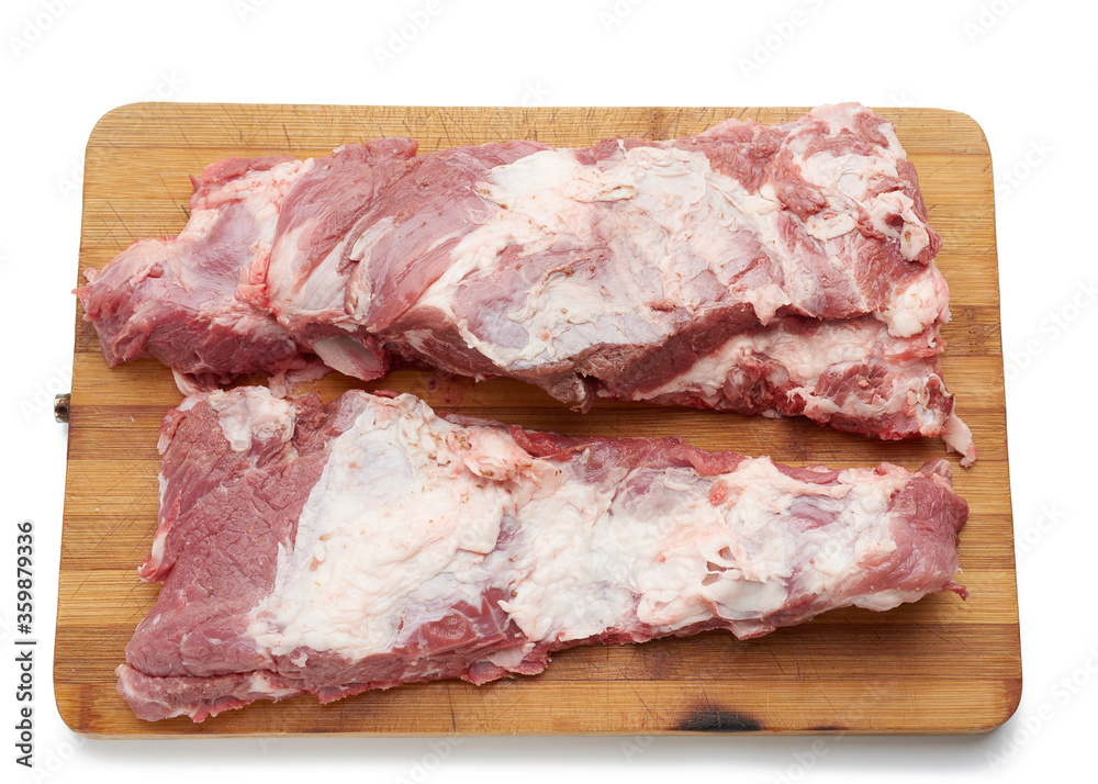 raw strip of pork meat on ribs with layers of fat on a wooden cutting board
